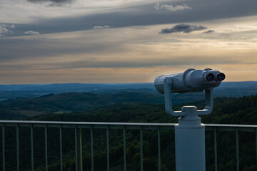Observation binoculars overlooking mountains. Scenic view from a viewing platform at sunset.