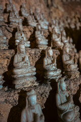 Fototapeta premium Large Buddha statue surrounded by smaller sculptures in Marble Mountains cave, Sacred cave temple with Buddha and statues in Marble Mountains Vietnam