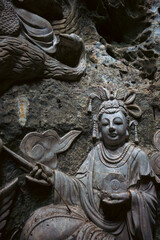 Sacred Buddha statue with phoenix carvings in cave temple, Spiritual cave shrine featuring Buddha statue and ritual offerings