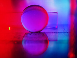 A clear glass ball is sitting on a pedestal. Colorful background. Abstract graphic background. Light effect. Planet in a space mood and feel.