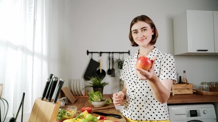 Energetic mother select fruit for making healthy food and looking at camera while hold fresh apple. Happy house keeper enjoy cooking while doing food preparation for making salad at kitchen. Pedagogy. - Powered by Adobe