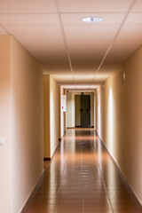Long hotel corridor with shining floor and doors