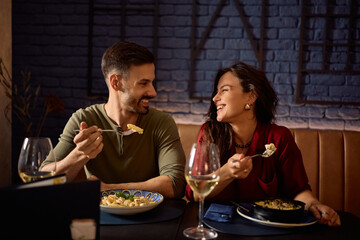 Happy couple communicating while eating in restaurant.