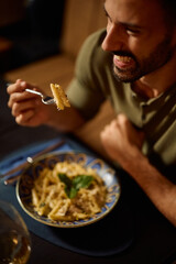 Close up of man eating pasta in restaurant.