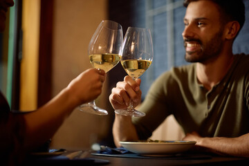 Close up of couple toasting with wine during a meal in restaurant.