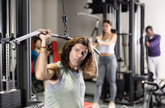 Caucasian man training on lat pull down machine in gym - Powered by Adobe