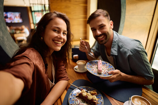 Happy couple taking selfie while enjoying in dessert in cafe and looking at camera. - Powered by Adobe