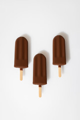 Chocolate ice cream popsicles on white background. Minimalist summer dessert concept
