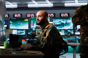 Counterterrorism division officer in war room using target acquisition tech to detect enemy...