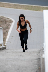 Determined sportswoman running up concrete stairs outdoors