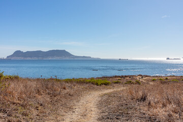 Gibraltar coast with rocky shore and cargo ship. Gibraltar, spain. september 2025.