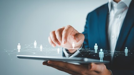 A businessman in a suit uses a tablet to manage a virtual network of people, symbolizing human resources and digital connection