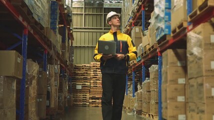Professional male worker wearing safety helmet working industrial warehouse storing and distributing logistics goods warehouse center using laptop record and monitor goods on the shelves. - Powered by Adobe
