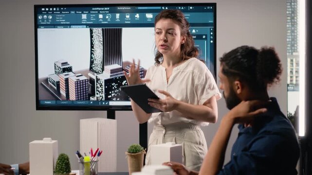 Female real estate contractor presenting structural blueprints and 3D models, engage in a meeting to finalize planning for urban development project aimed at infrastructure growth. Camera B.