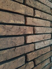 A brick wall with uneven and weathered rectangular bricks in varying shades of brown and red.