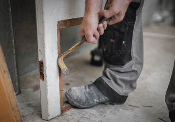 One young worker is pulling out nails with a crowbar.