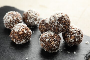 Tasty chocolate candies with nuts and coconut flakes on light table, closeup