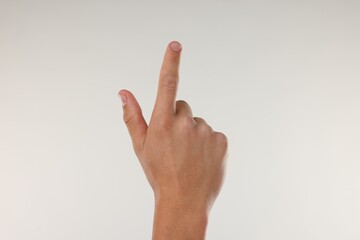 Fototapeta premium Man touching something on light grey background, closeup