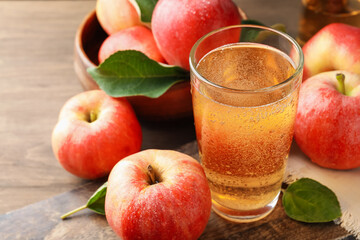 Delicious cider in glass, apples and leaves on wooden table, closeup