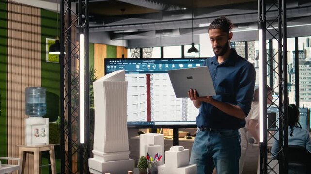 Male real estate engineer studying smart city design and buildings layout, creating a master plan for modern residential infrastructure growth and property investment. Camera A.