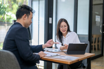 Businesspeople working together using tablet and documents at office desk