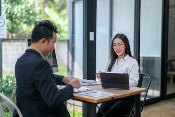 Business people working together in modern office analyzing charts and reports on computer and tablet