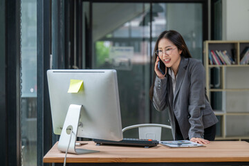 Fototapeta premium Businesswoman talking on phone and working on computer in office