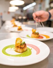 Close-up of plated scallops, garnished with citrus and sauces.  Chef's hand using tongs to arrange a dish