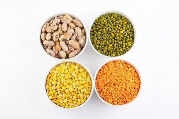 Fototapeta premium Four bowls of different types of dried legumes and lentils on white background