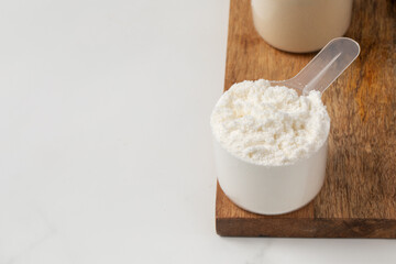 Protein powder scoop on wooden board for health and fitness nutrition concept. Copy space
