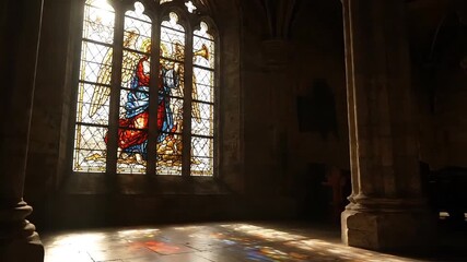 Sunlight streams through a vibrant stained glass window in a grand, ancient building, casting colorful patterns on the floor. - Powered by Adobe