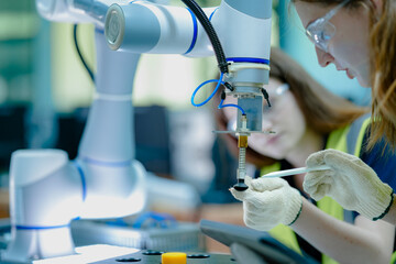 Two female students in a technology class work with robotic arms. They are learning about programming and automation, preparing for careers in engineering and advanced manufacturing. © ultramansk