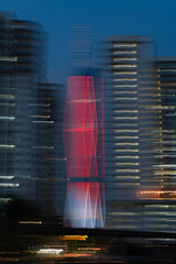 Artistic motion blur photo of Menara 118 illuminated in red at night, surrounded by nearby high-rise buildings in Kuala Lumpur, Malaysia.