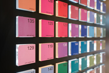 Color swatch display with neatly arranged square tiles showing various shades, each labeled with its name and number on a black background.