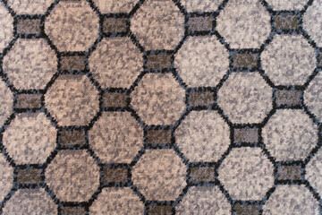 Naklejka premium Textured carpet surface with repeating octagonal pattern in shades of grey and blue, forming a geometric grid design.