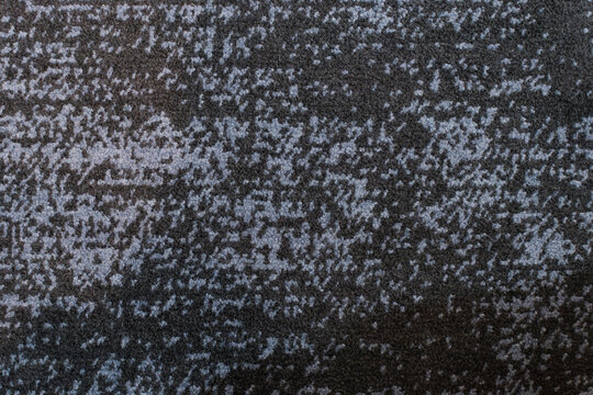 Close-up of textured dark grey and blue carpet with irregular pixel-like pattern.