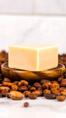 Beige soap bar on wooden dish, cocoa beans