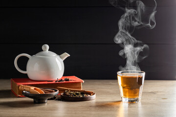 Hot tea in a glass with steam. Teacups placed on the table with a white jug in the warm atmosphere of morning sunlight.