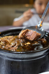 Close-up of a Steaming Pot of Braised Meat Being Served with a Spoon
