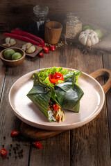 Traditional Asian Rice Wrap with Leaf Wrap and Fresh Vegetables on Rustic Wooden Table