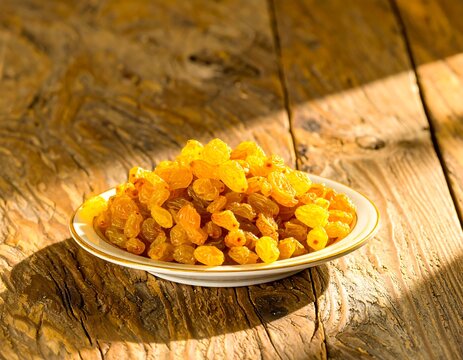 Pile of golden raisins on a white plate on a rustic wooden surface
