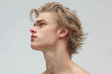 young man with wet eyelashes and heavy breathing stands against clean solid background