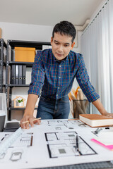 Young architect working in office with building models and floor plans, analyzing details and creating innovative design concepts, showing creativity, focus, and dedication in architecture projects.