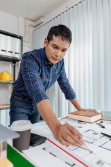 Young architect working in office with building models and floor plans, analyzing details and creating innovative design concepts, showing creativity, focus, and dedication in architecture projects.