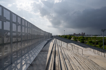 Fototapeta premium Metal Fence Along Elevated Railway Track Under a Stormy Sky in an Urban Setting