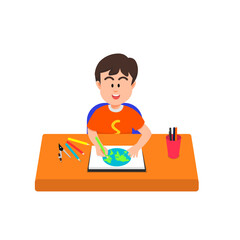 Happy boy colors a drawing of the earth in his sketchbook using colored pencils