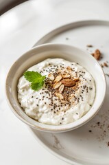 Fresh Cottage Cheese with Chia Seeds and Ground Cinnamon in White Ceramic Bowl on Minimal Bright Table