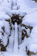 Dug trench with pipe covered in snow. Pipeline installation work in cold winter weather concept. Building, work of public utilities