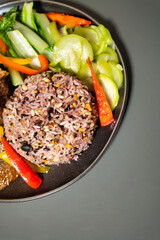 Colorful Mixed Grain Rice with Fresh Vegetables Served on a Black Plate