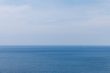 Fototapeta premium 青い海と空、水平線と白い漁船